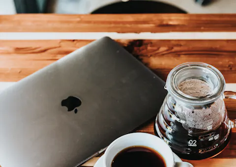 A work desk with a laptop and a cup of coffee